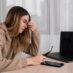 Image of a frustrated woman in front of a laptop